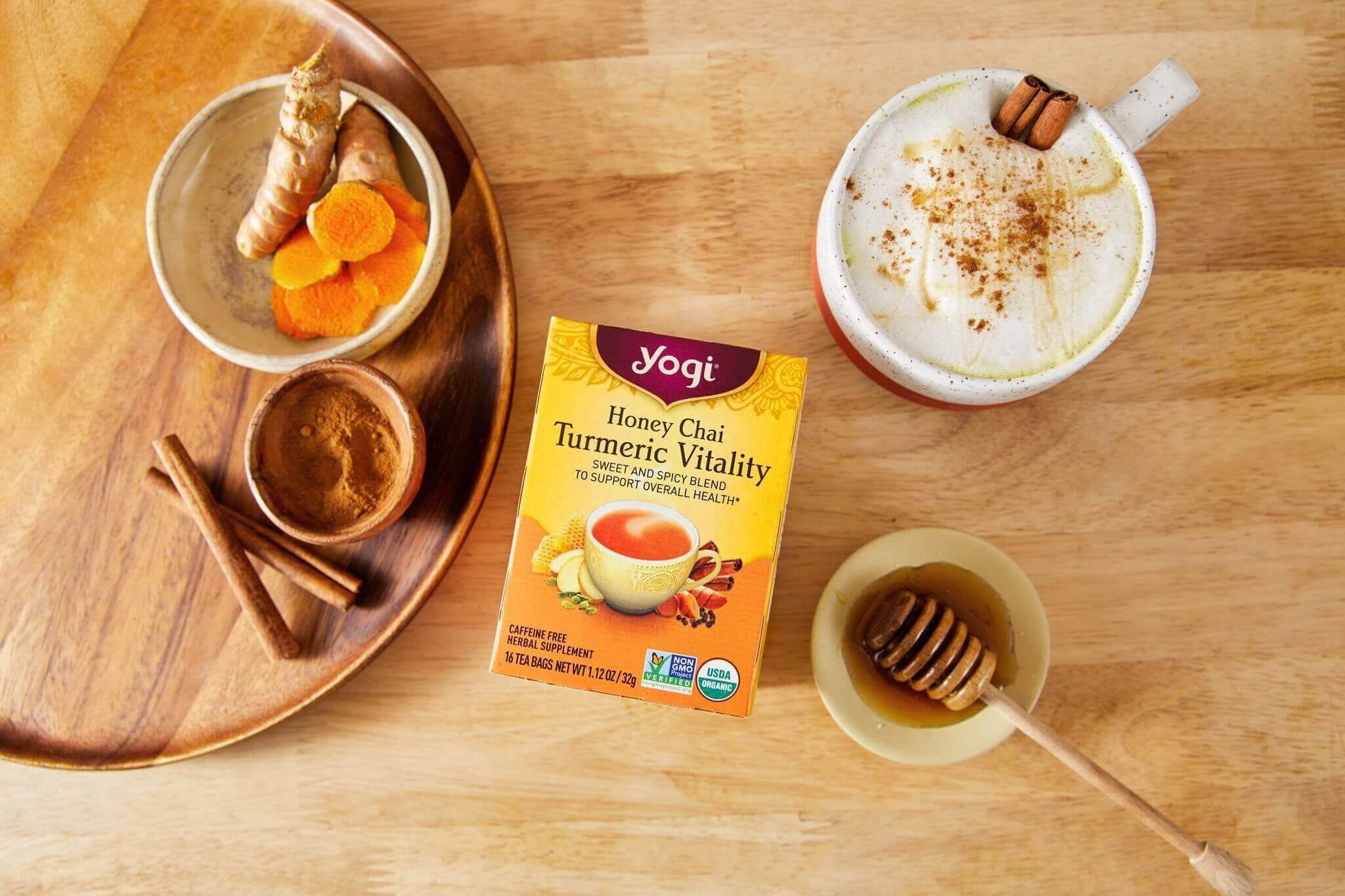 A mug of Honey Golden Milk Latte sits on a counter next to a carton of Yogi Honey Chai Turmeric Vitality Tea