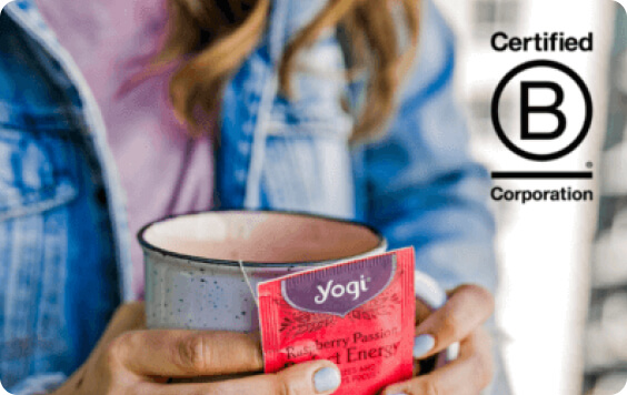 Hands holding a mug of tea with a 'Raspberry Passion Perfect Energy' Yogi Tea bag, next to the Certified B Corporation logo.